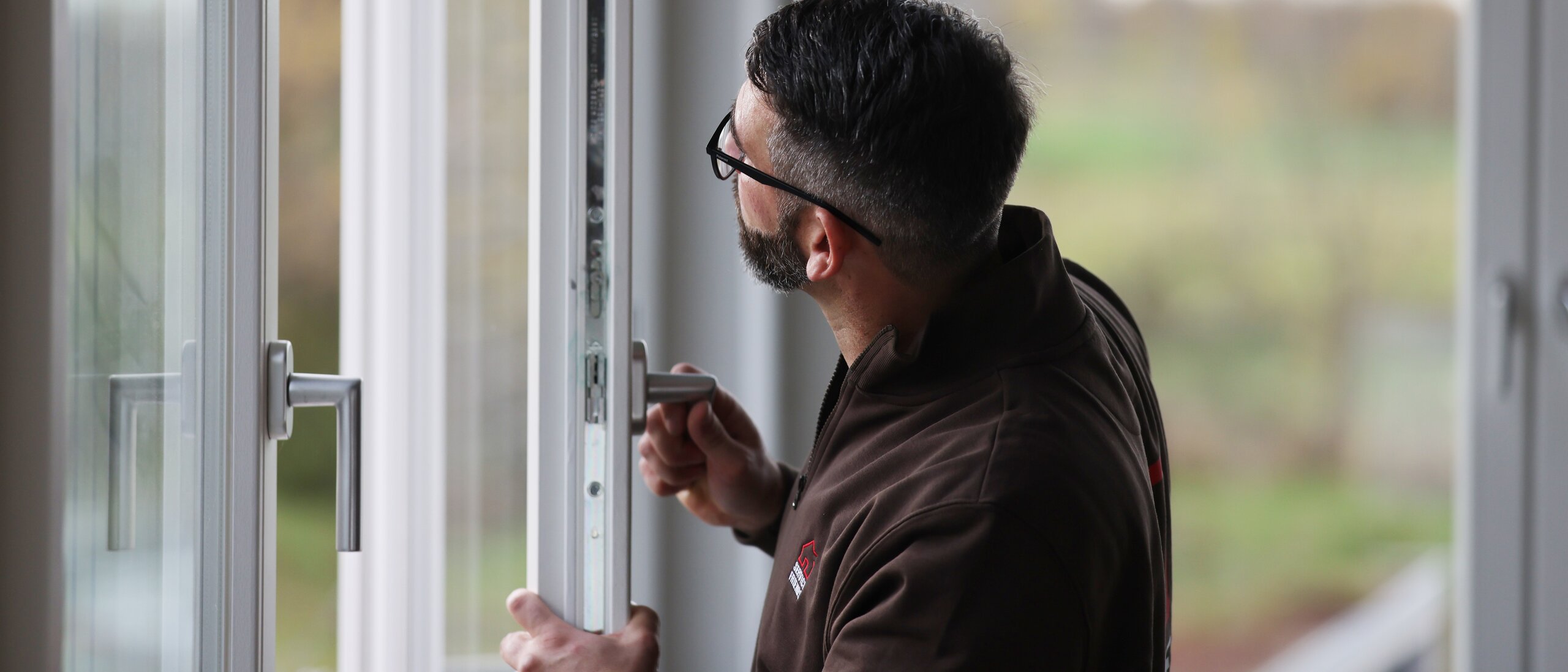 Ein Mann der einen offenen Fensterflügel in der Hand hält und ihn untersucht.