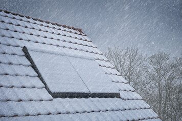 Ein Dach mit 2 Dachfenstern welche mit Schnee bedeckt sind